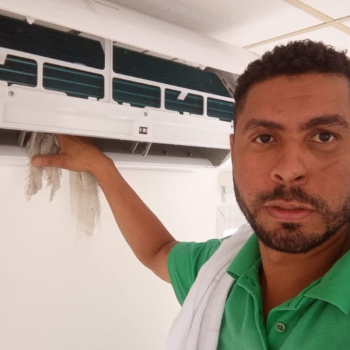 Profissional realizando limpeza em uma unidade interna de ar-condicionado